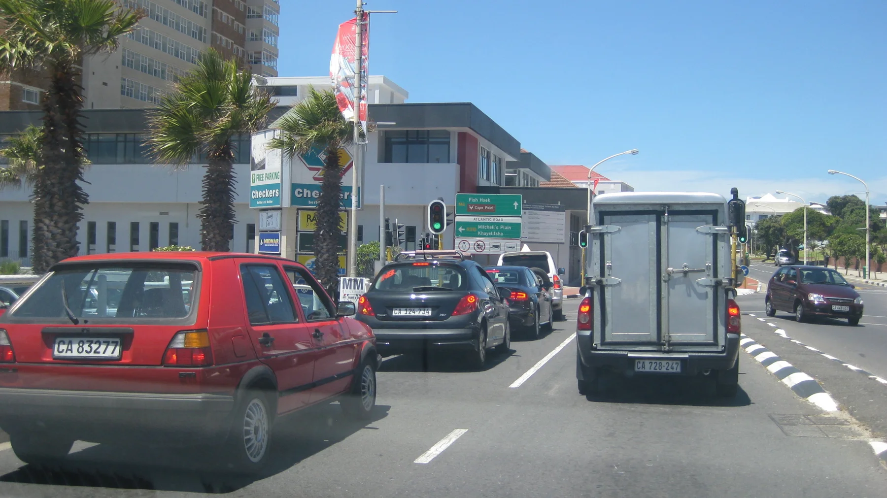 A van and several cars travel along a busy town street.