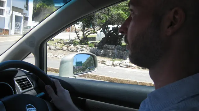 A driver is seen in profile inside a car during the journey.