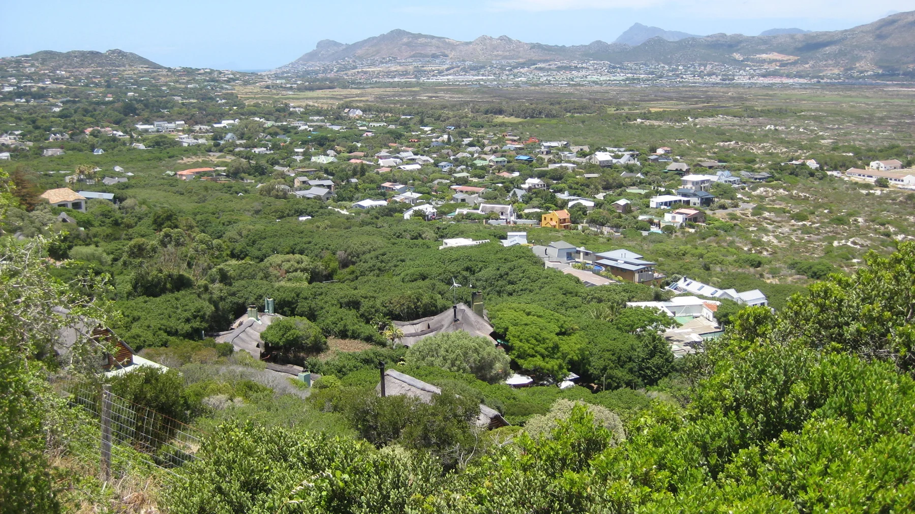 Scattered houses sit among green slopes with mountains stretching across the distance.