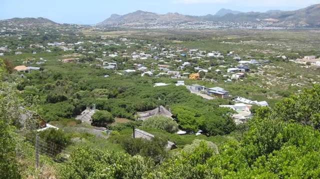 Scattered houses sit among green slopes with mountains stretching across the distance.