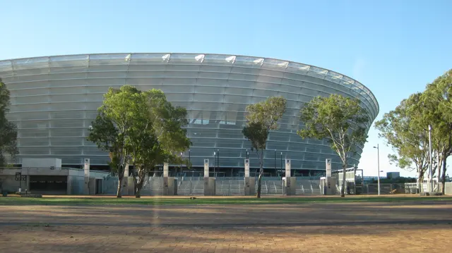 Trees and palms frame another view of the broad silver stadium.