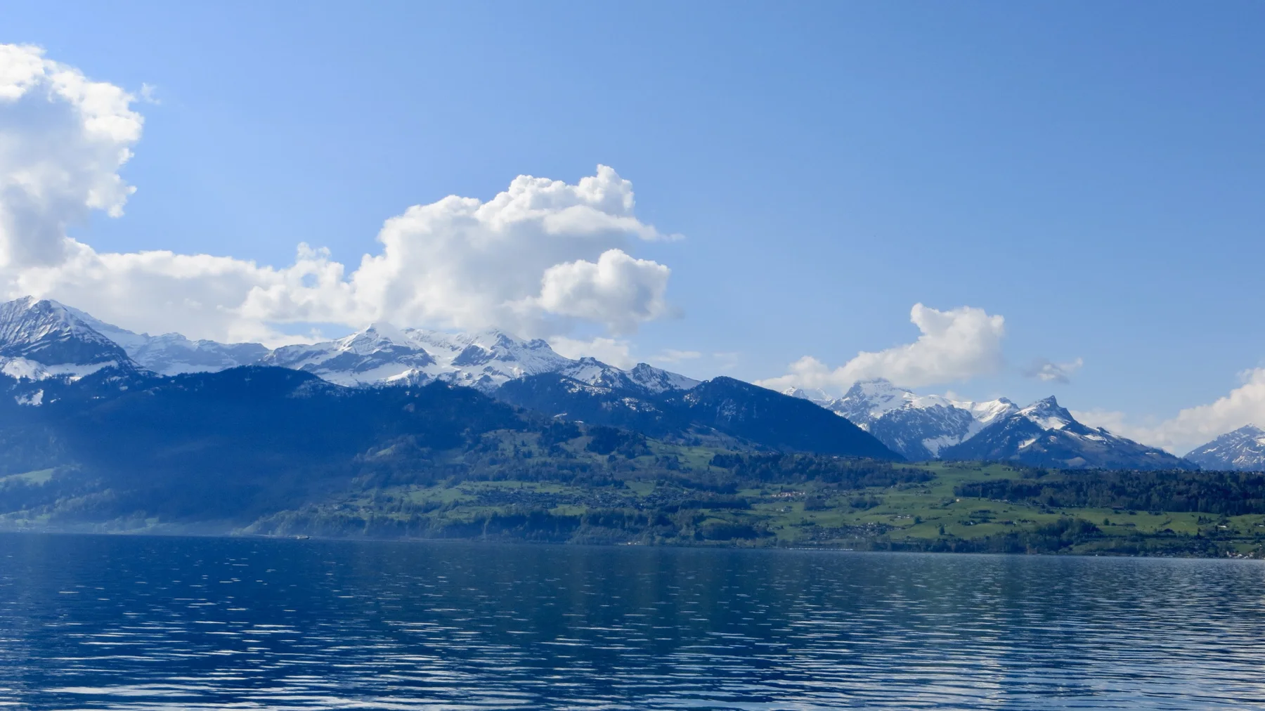 Snow-covered mountains stretch across the far side of a blue lake.