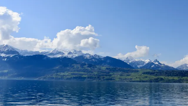 Snow-covered mountains stretch across the far side of a blue lake.