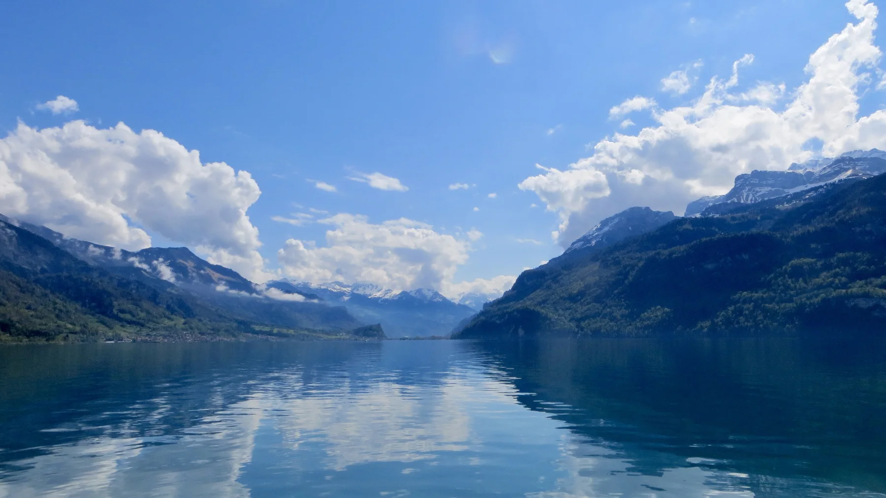 Mountains and clouds form a broad reflection along a quiet lake.