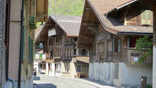 Traditional wooden houses with balconies line a narrow village street.