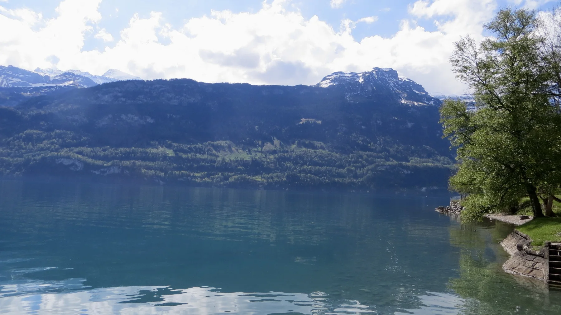 A dark mountain ridge with snow near its top rises across the lake.