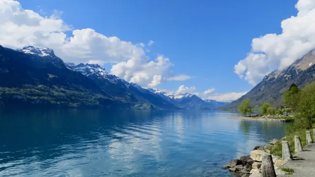 Low stone posts line the near shore of a broad lake below mountain ridges.