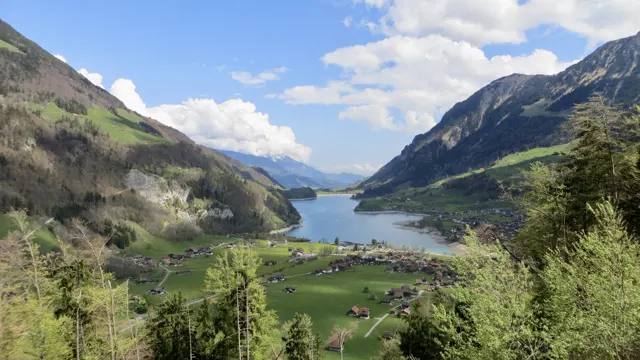 Village roofs and green slopes lead toward a long lake in the mountain valley.