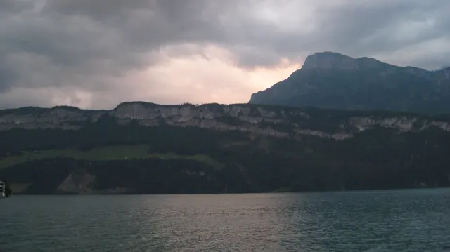 A pale band of light glows behind a dark ridge across the lake.