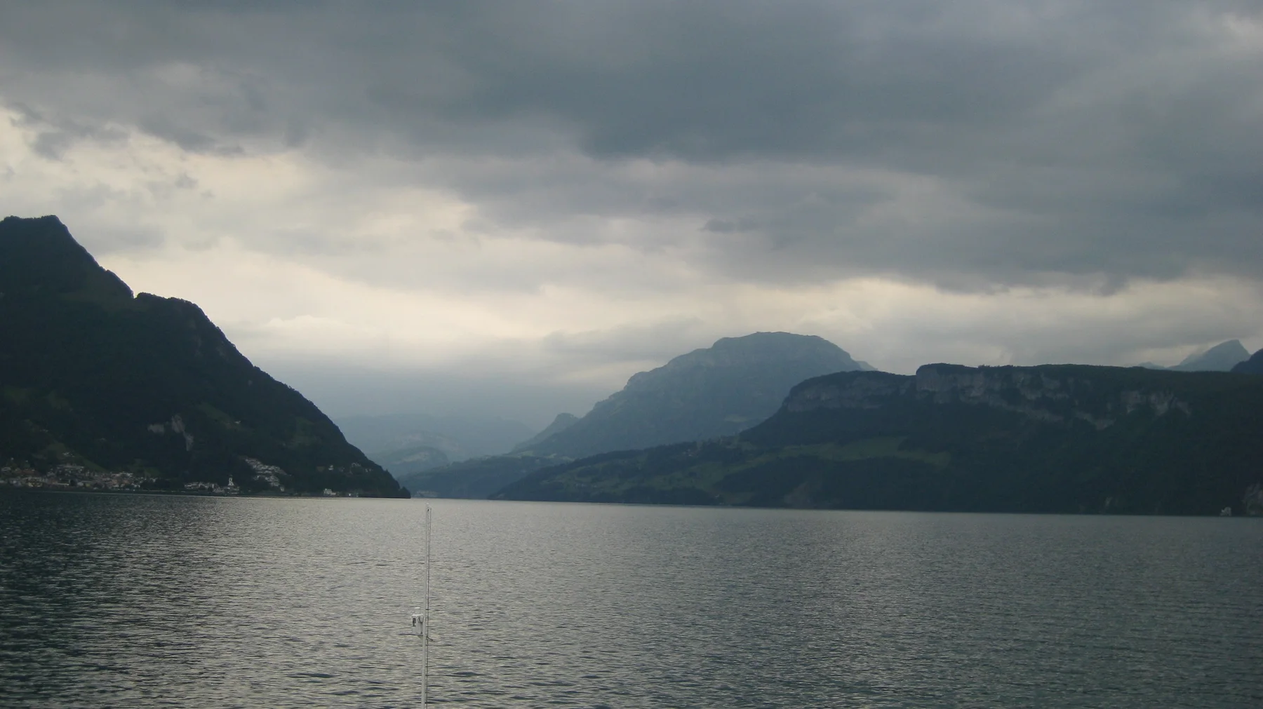 A lake narrows between dark mountain slopes beneath heavy clouds.