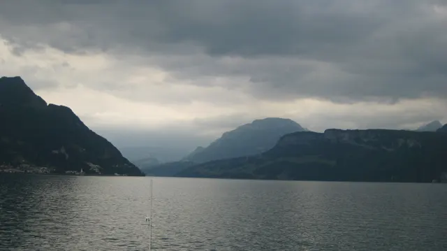 A lake narrows between dark mountain slopes beneath heavy clouds.