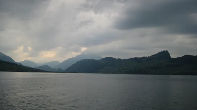 Layered mountains stretch beyond open lake water under a thick cloud ceiling.