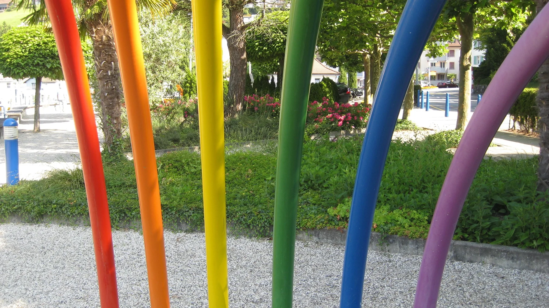 Red, orange, yellow, green, blue and purple poles stand beside a garden path.