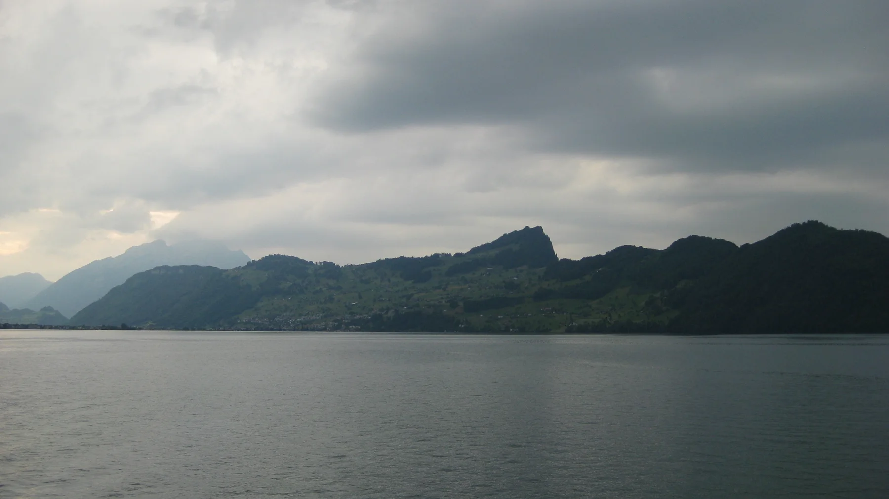 A long, uneven mountain ridge stretches across the far side of a gray lake.