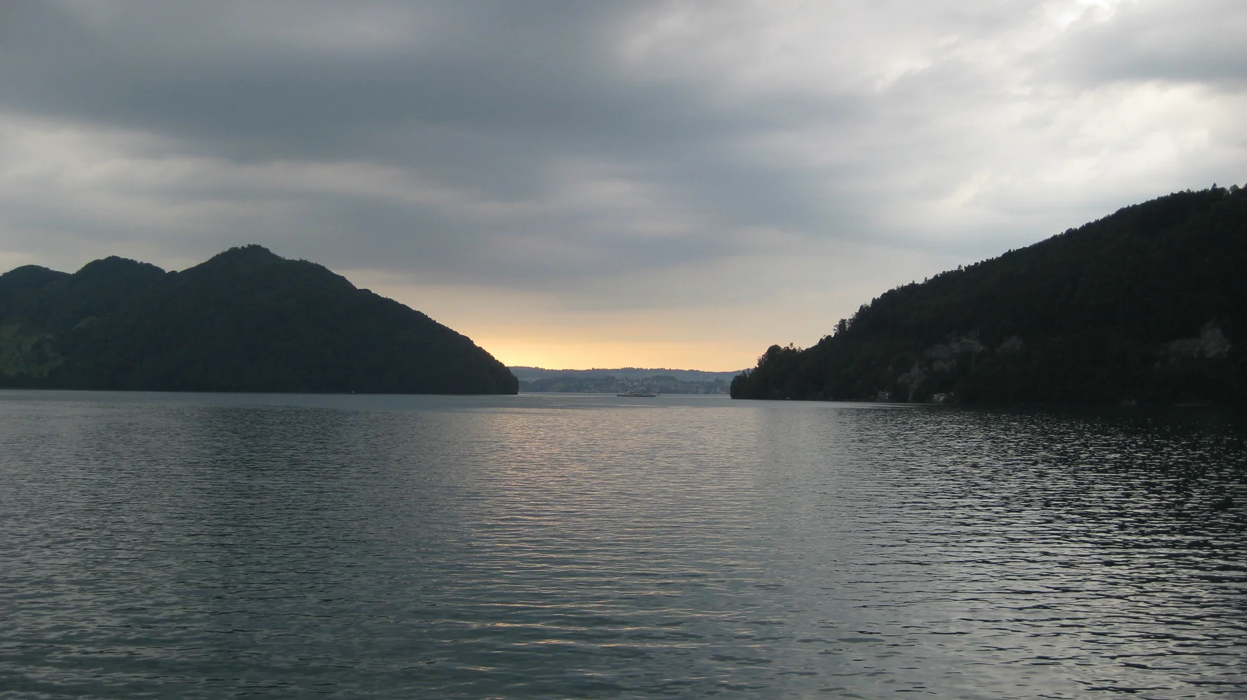 A pale golden opening beneath the clouds lights the distant end of the lake.