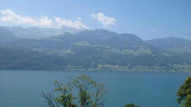 A blue lake fills the foreground beneath a long range of green mountains.