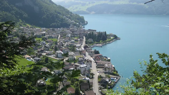 An elevated view follows village buildings and roads around a blue lakeside bay.