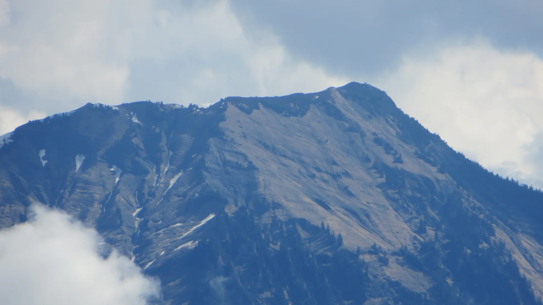 A broad rocky mountain face rises between patches of cloud.