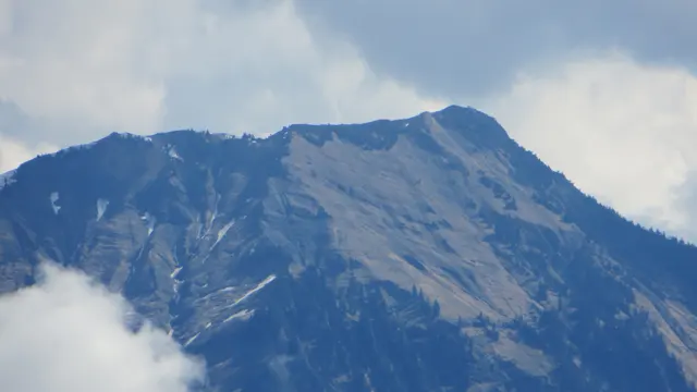 A broad rocky mountain face rises between patches of cloud.
