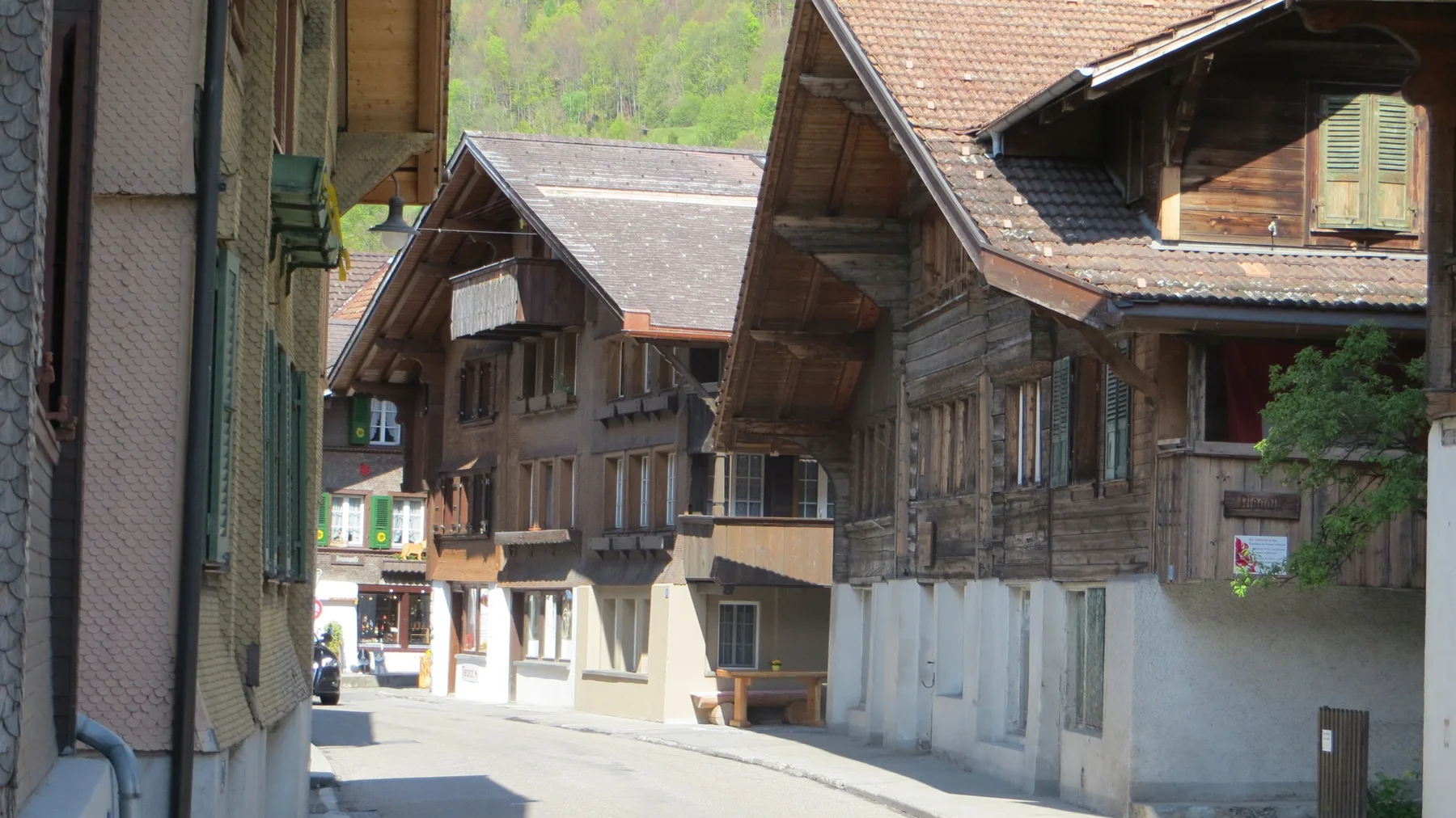 Wooden chalets with shutters and balconies line a quiet village street.