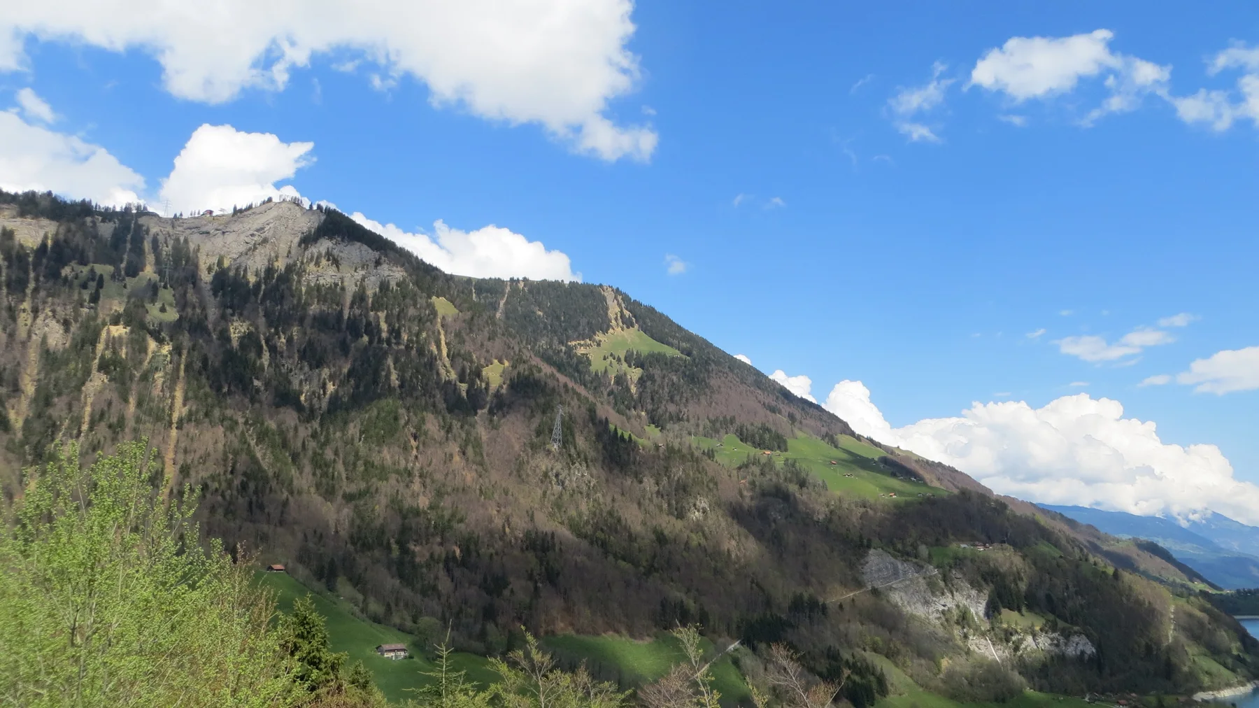 A jagged, forested ridge stretches beneath a blue sky with small white clouds.