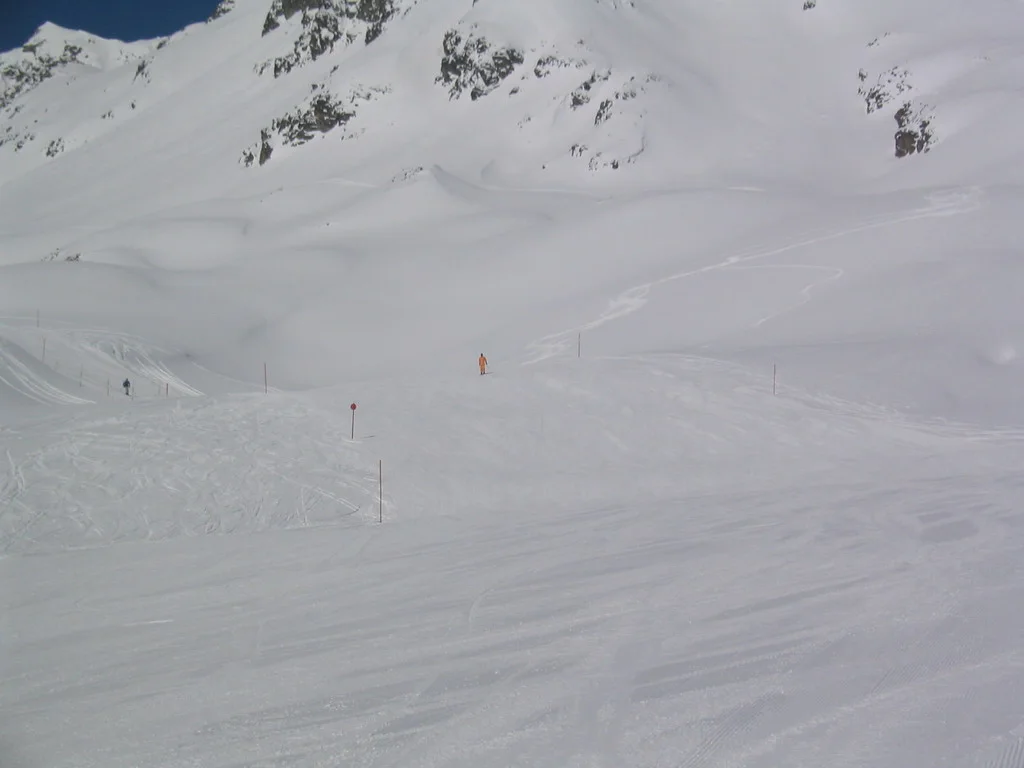 Faint tracks and small figures mark a wide, pale snow-covered slope.