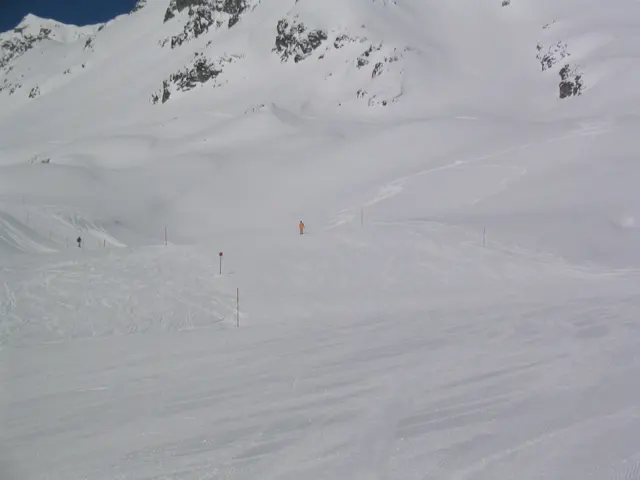 Faint tracks and small figures mark a wide, pale snow-covered slope.