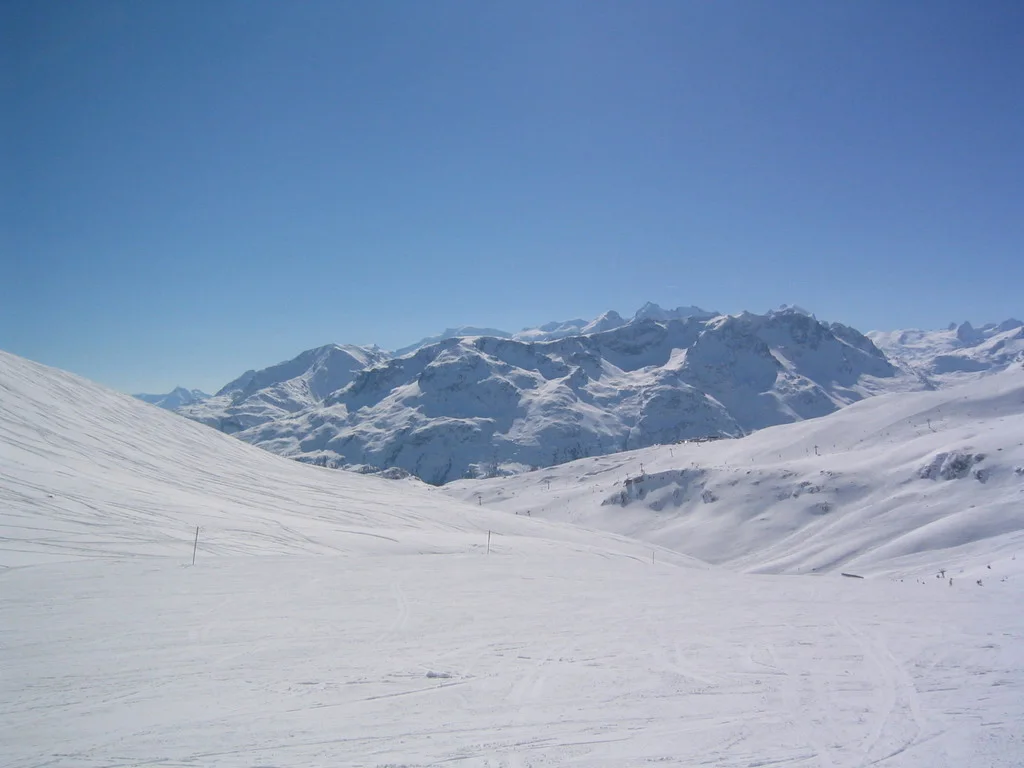 A wide snowfield leads toward overlapping snowy mountain ridges.