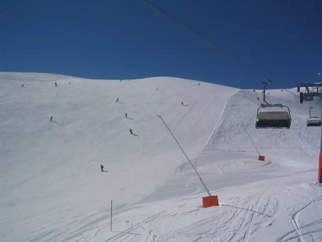 Chairlift cables and suspended chairs cross a broad, sunlit ski slope.