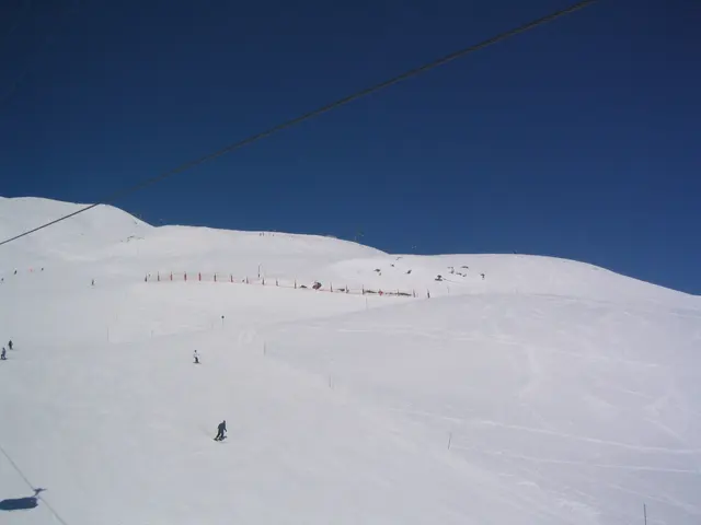 Scattered skiers cross a broad, gently rising snowfield.