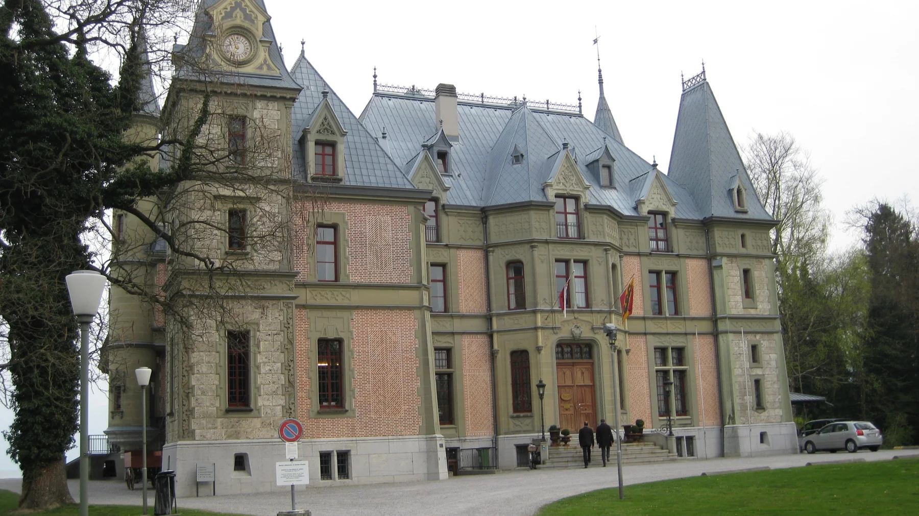 Decorative stonework and steep gray roofs shape the facade of a large historic-looking building.