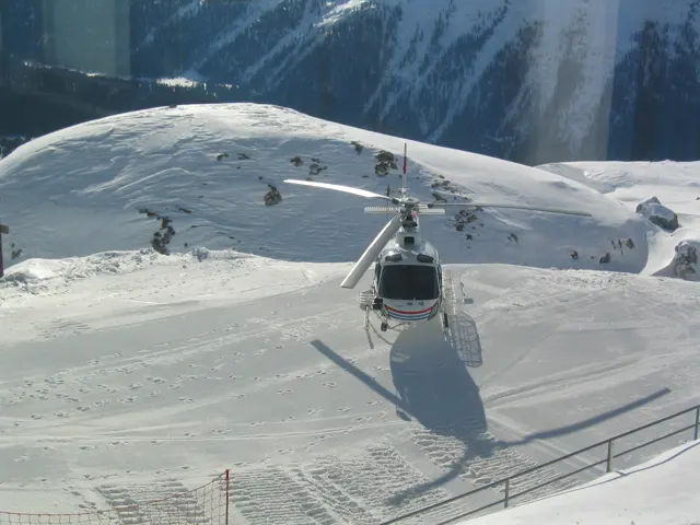 A gondola cabin hangs above a snowy slope, casting a long shadow below.