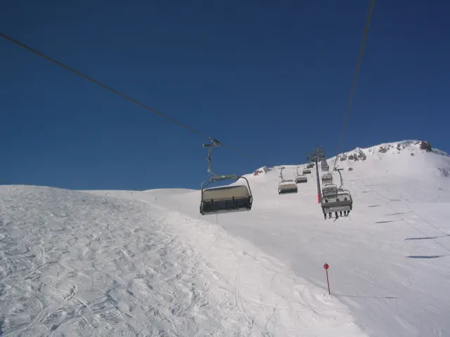 Chairlift seats pass a rough snowbank on their way up the mountain.