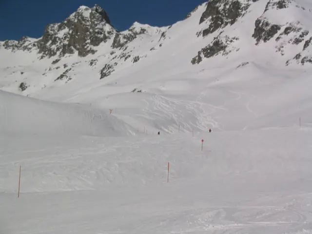 Rolling snowfields lie below a broken line of dark mountain crags.