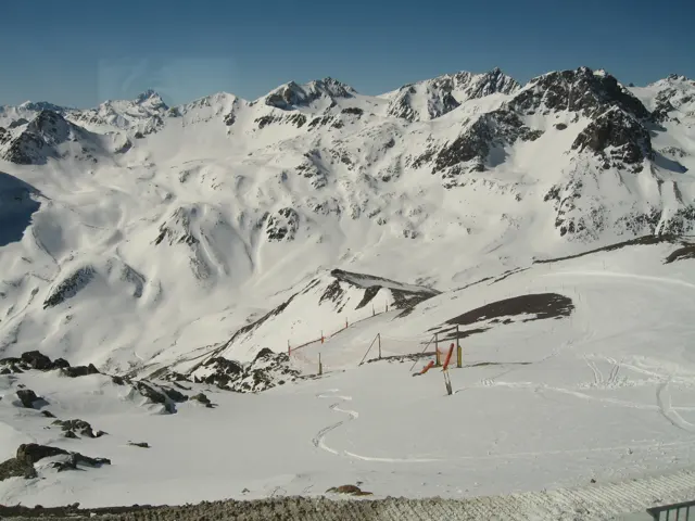 Ski tracks and lift structures cross a broad snowy basin below jagged peaks.