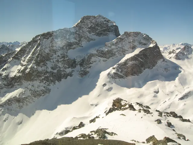 Rugged rock shoulders rise from deep snow with smaller peaks stretching into the distance.