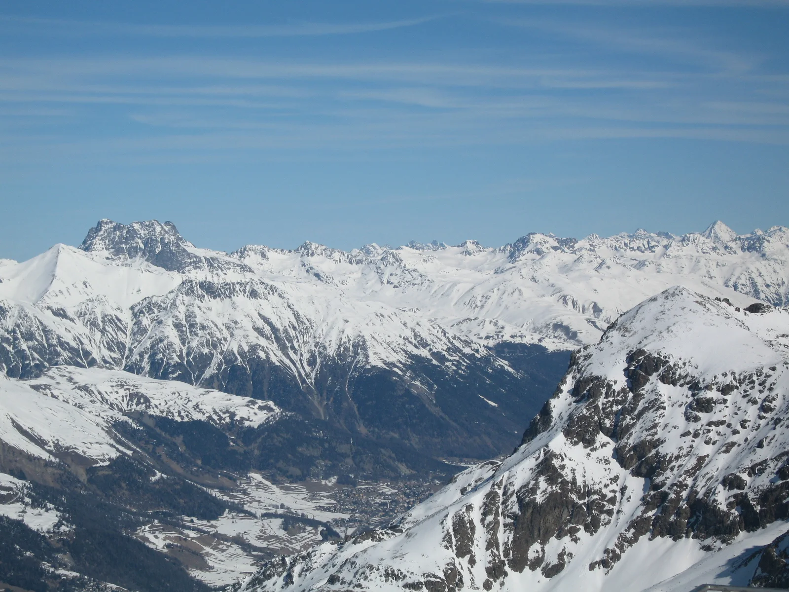 Snowy ridges enclose a deep valley seen from high above.