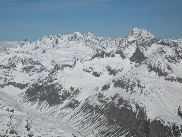 Successive jagged peaks and snow-filled gullies stretch across a wide mountain panorama.