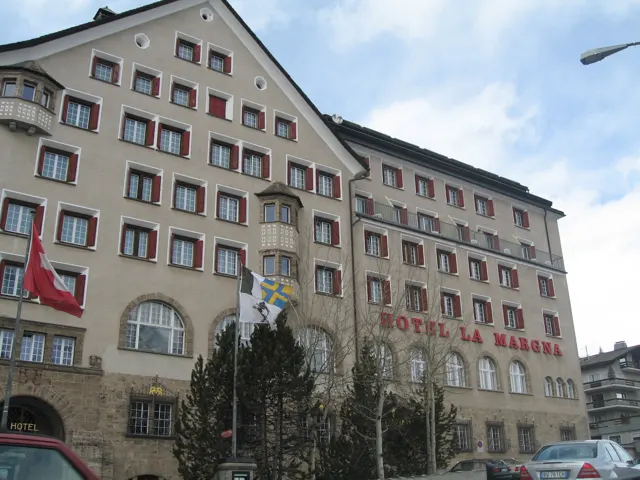 Rows of windows and projecting balconies fill a tall hotel facade under a partly cloudy sky.