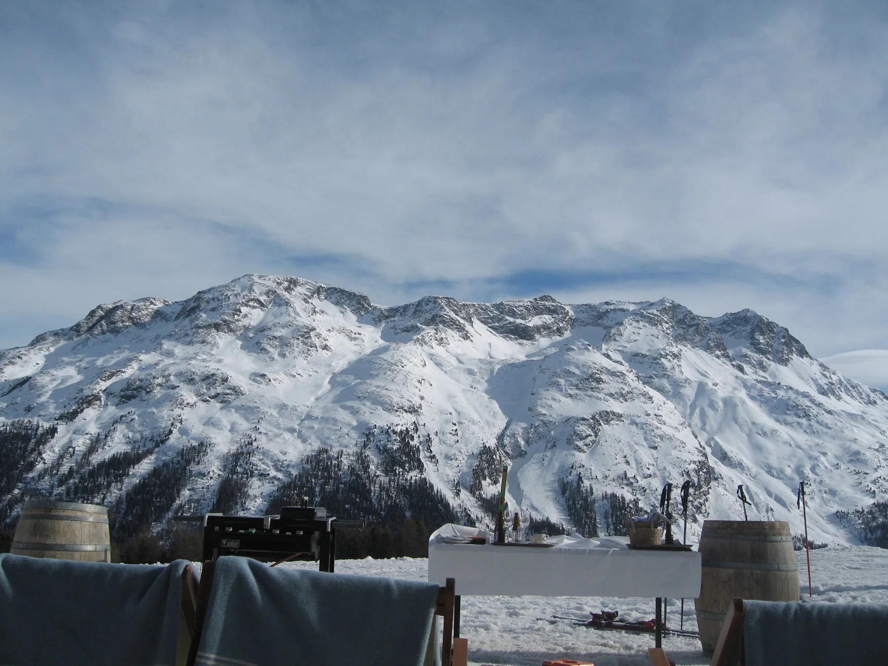 Outdoor seats face a broad snowy mountain ridge beyond a terrace.
