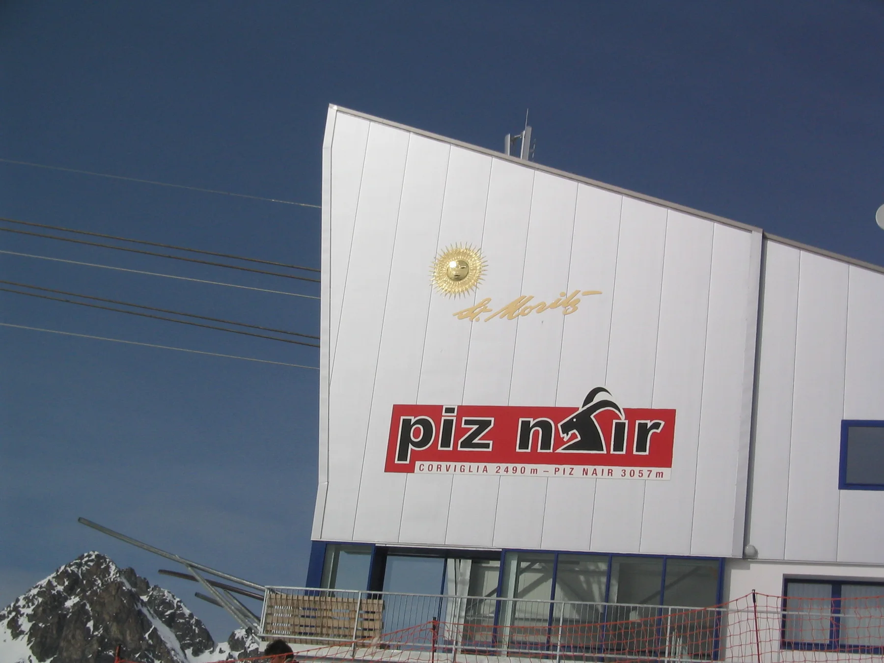 A building facade carries a Piz Nair sign beneath a clear blue sky.