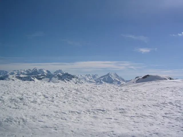 Rough, sparkling snow fills the foreground beneath a distant line of peaks and blue sky.